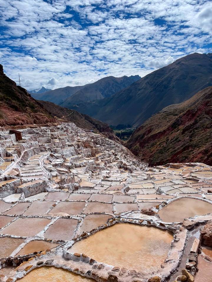 Expansive salt terraces of Maras glisten in a steep valley framed by rugged Andes peaks.