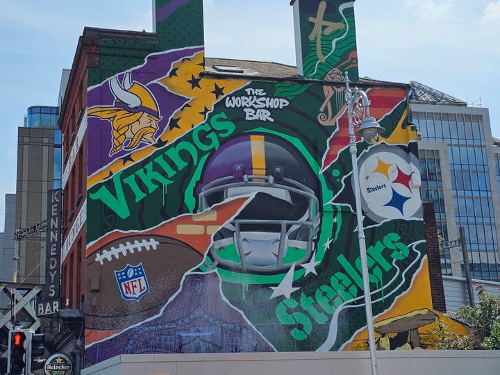 Colourful sports themed street mural featuring NFL helmets on a city building
