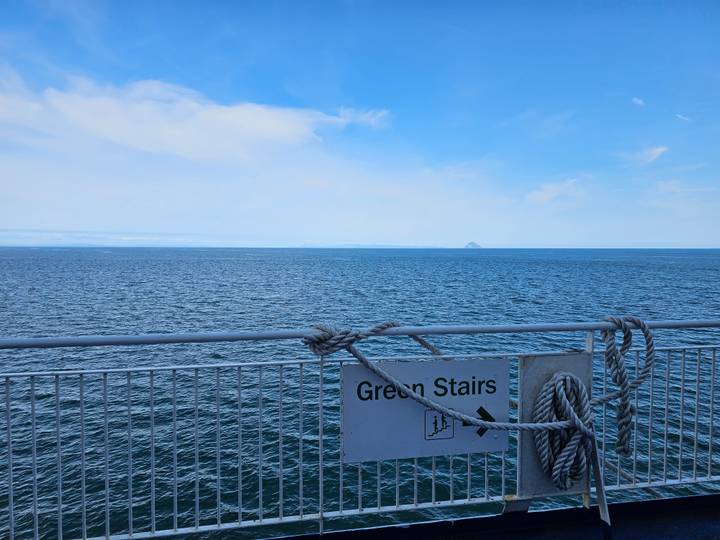 Wide seascape from a ferry deck with ropes and a sign reading Green Stairs