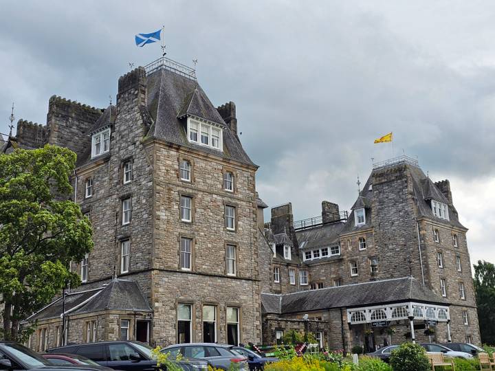 Historic stone hotel or castle-like building with turrets under grey skies