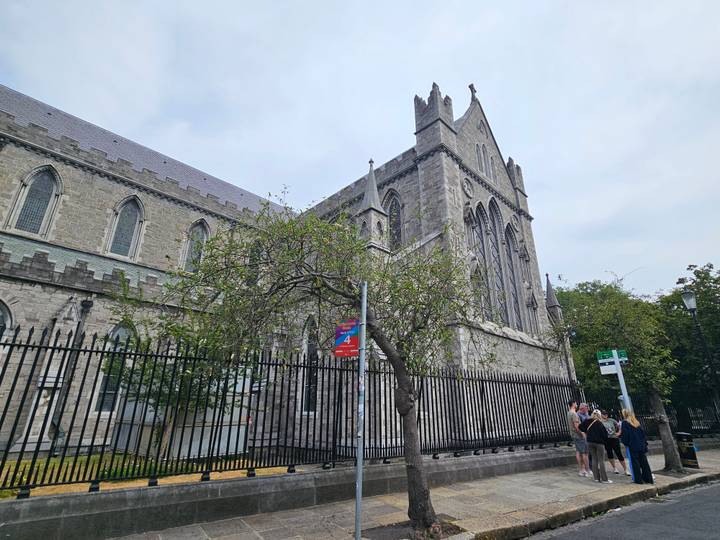Angled exterior shot of St Patrick’s Cathedral Dublin with iron fence and tourists at corner