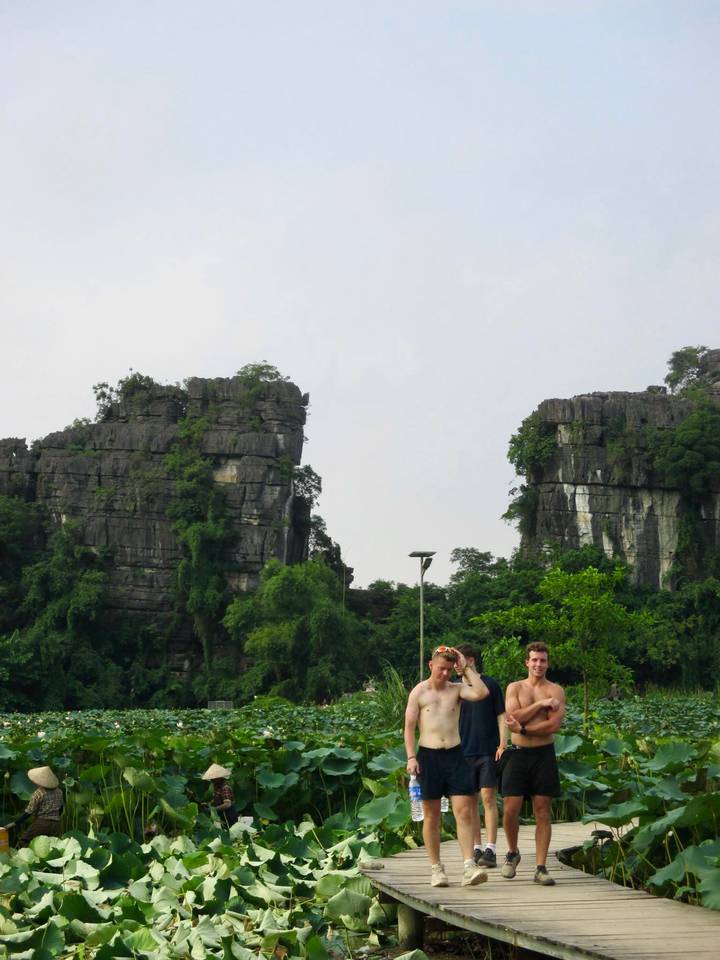 Limestone karst towers rise behind two smiling travellers posing in lush green scenery