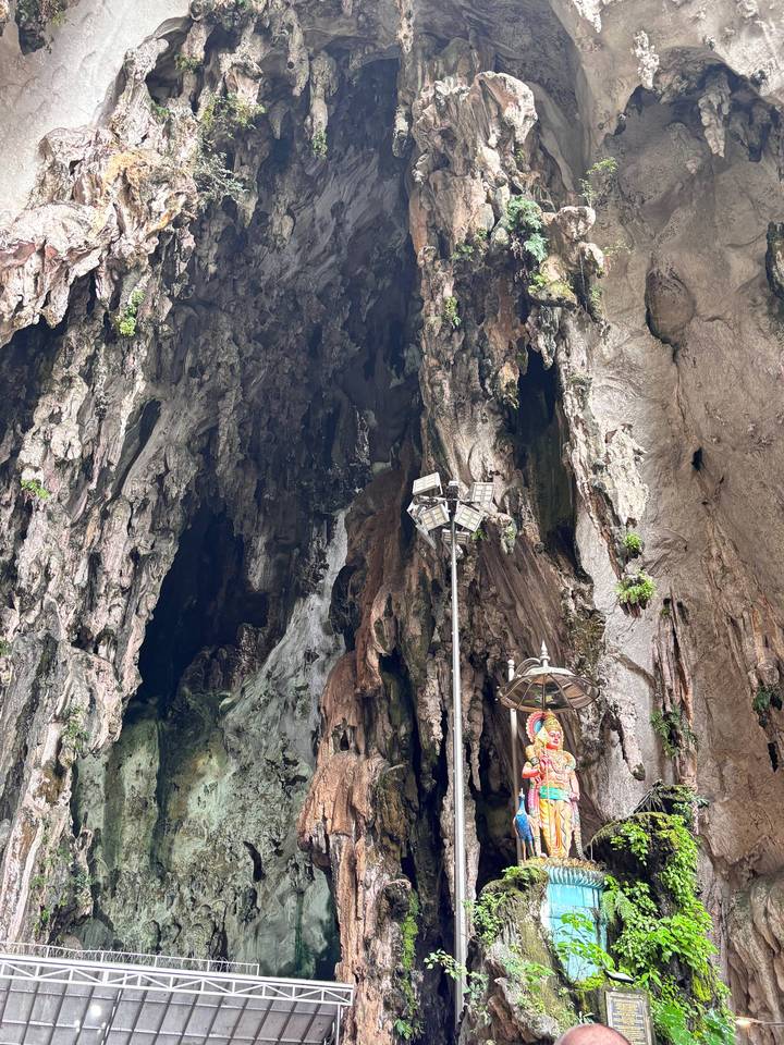 Rugged interior of Batu Caves with towering rock walls and Hindu shrine elements