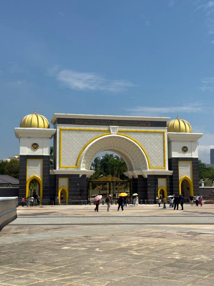 Istana Negara main gate in Kuala Lumpur with yellow domes and ornate Islamic arch design on a sunny day.