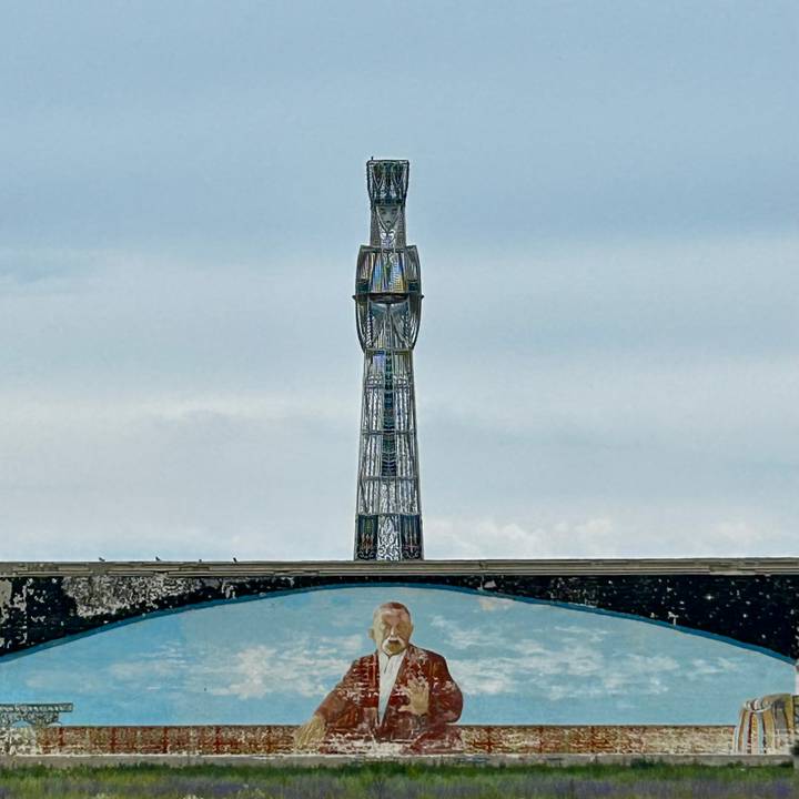 Tall steel communications tower rising above a mural of a cosmonaut against a cloudy sky.