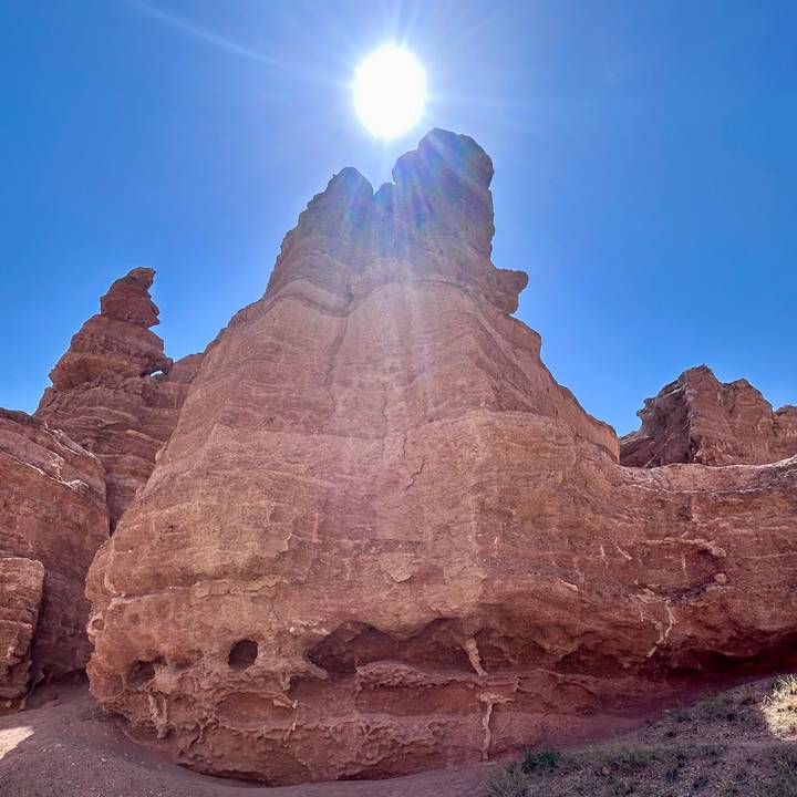 Towering red sandstone pillars of a canyon lit by strong sunlight from above.