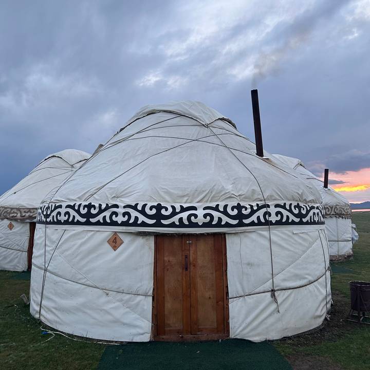 Close view of a traditional circular yurt with decorative black patterns at sunset.