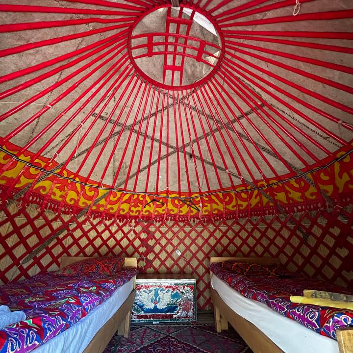 Interior view of a yurt roof with red wooden spokes and ornate patterns