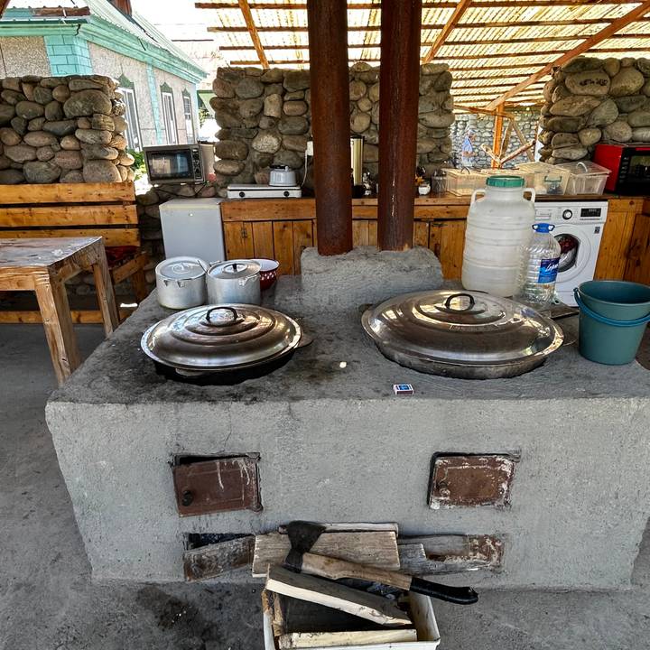 Rustic outdoor kitchen stove with two large metal pots and simple utensils