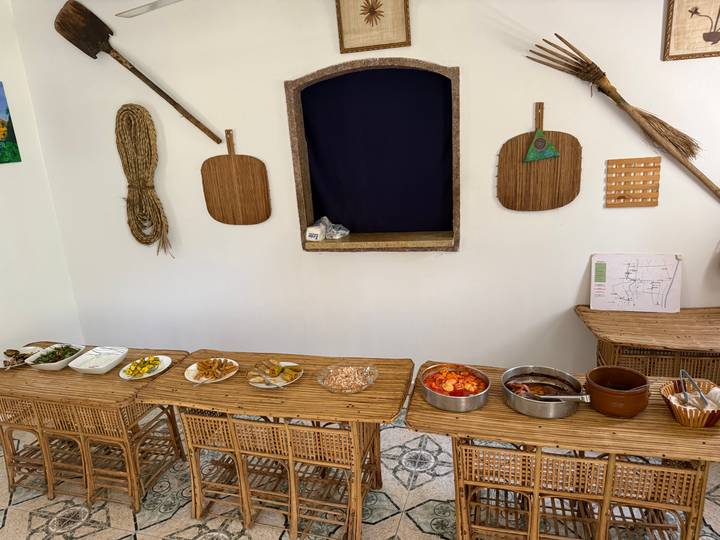 Simple buffet layout with assorted Egyptian dishes on wicker tables against a white wall.