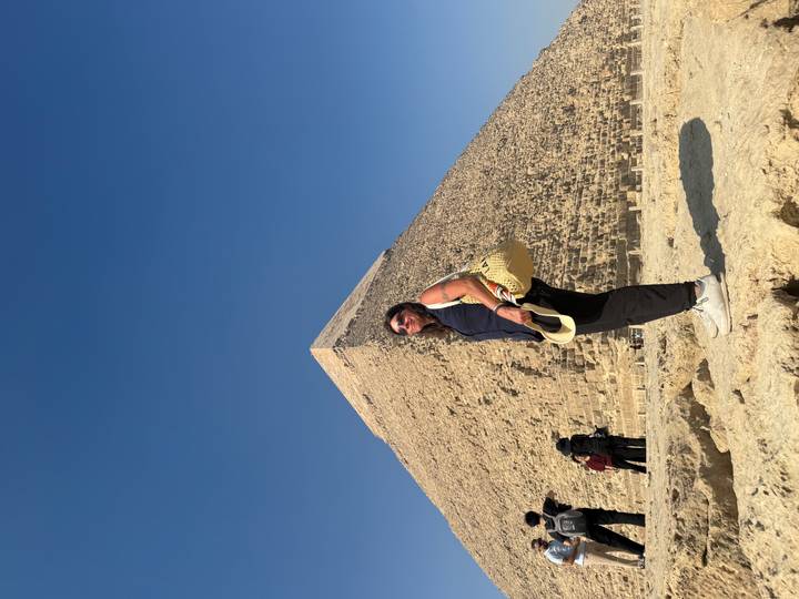 Woman posing in front of the Great Pyramid of Khafre under a bright blue sky.
