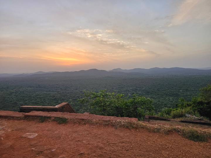 Golden sunset over an endless green forest and distant hills viewed from a cliff