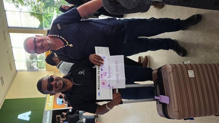 Guide welcoming traveller at an airport arrivals hall holding a personalised sign.