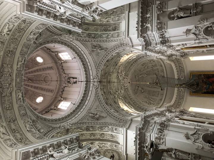 Lavishly decorated white baroque church ceiling with ornate stucco and central dome.