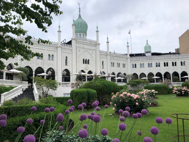 Moorish-style white façade of the Nimb Hotel with arches, domes and lush flower garden in front.