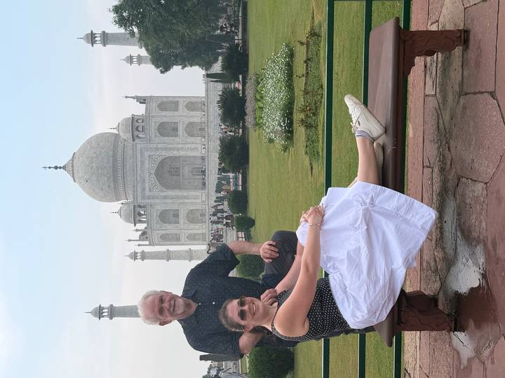 Couple sitting on a bench with the Taj Mahal rising majestically in the background.