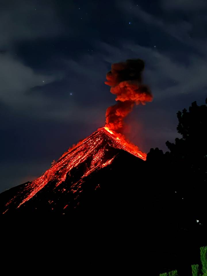 Nighttime volcanic eruption with glowing lava river cascading down the slope