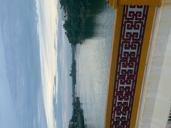Vertical view of a tranquil river under pastel dawn sky framed by decorative bridge railing