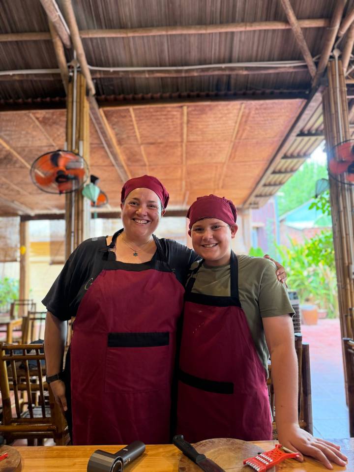 Mother and son wearing burgundy chef hats and aprons during a cooking class