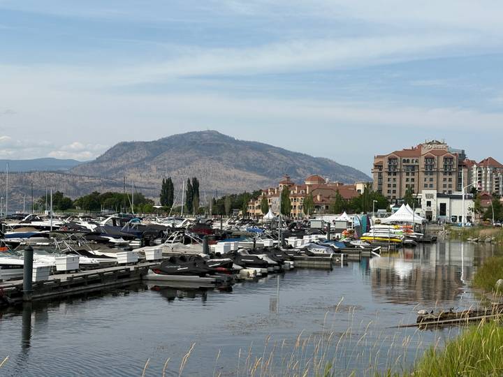 Modern marina filled with boats and jet skis set against lakeside resorts and arid mountains.