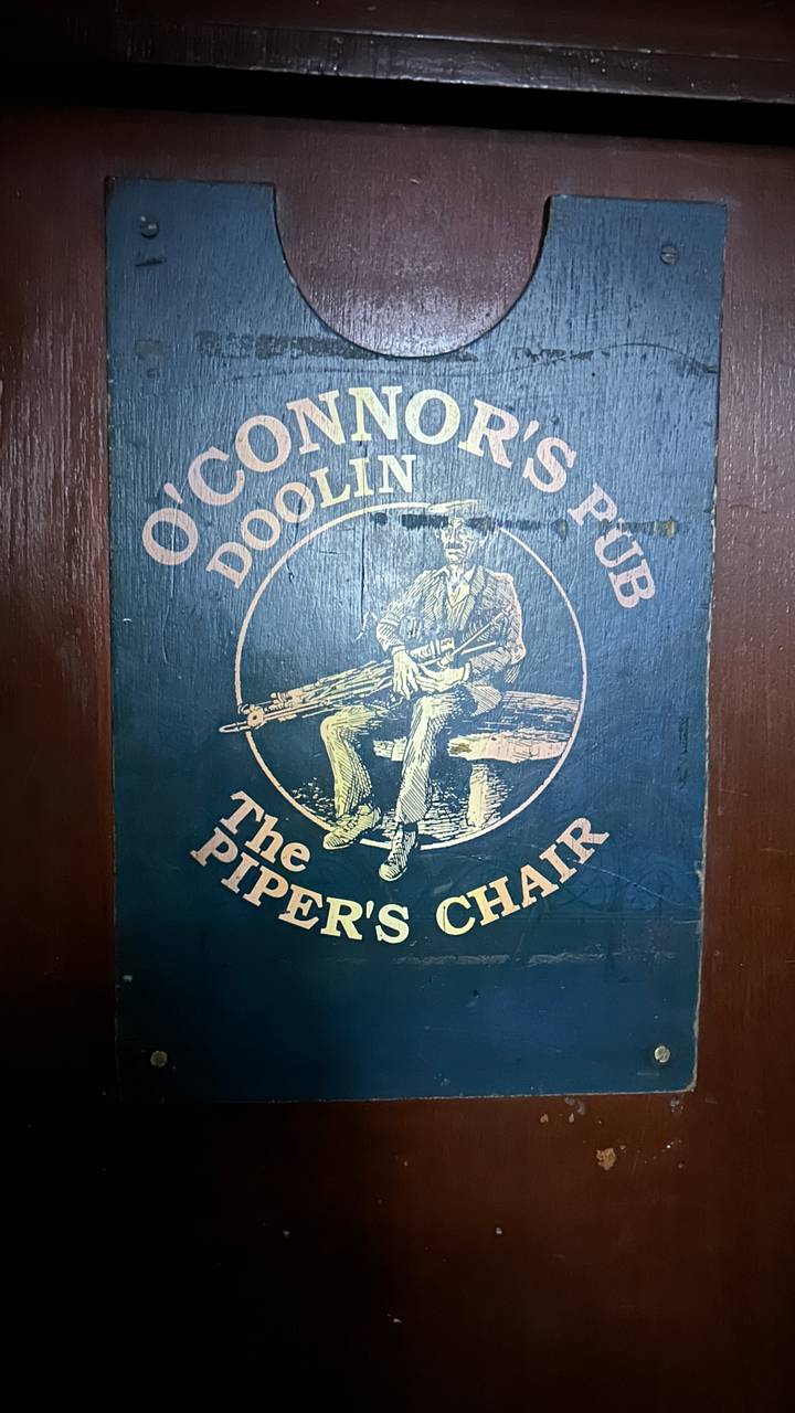 Pub sign for The Piper's Chair painted on wooden door.