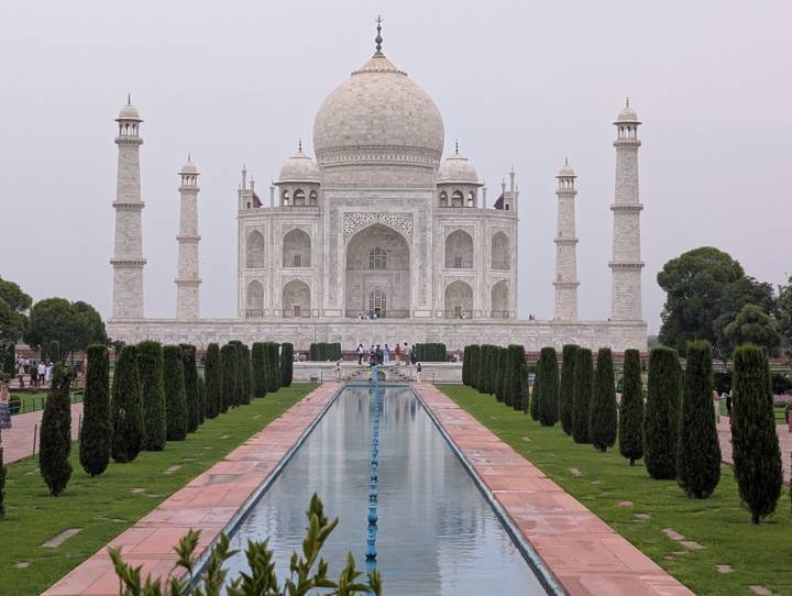 Centered view of the Taj Mahal and its reflecting pool on a hazy afternoon.