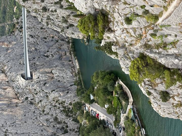 Emerald river winds through steep limestone cliffs beneath a modern bridge in a narrow gorge.