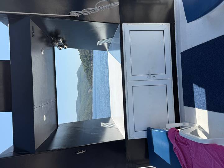 Open deck area of a yacht looking out to calm blue sea and forested islands.
