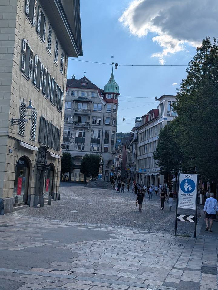 Cobblestone pedestrian street lined with historic European buildings and shoppers