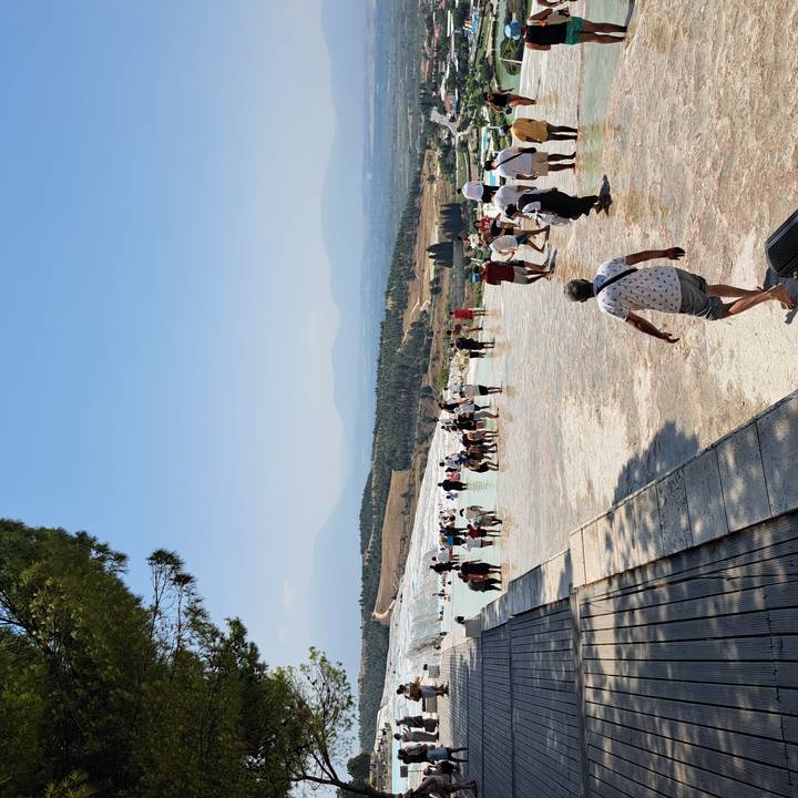 Visitors wading in the turquoise terraces of Pamukkale with hazy mountains in the background.