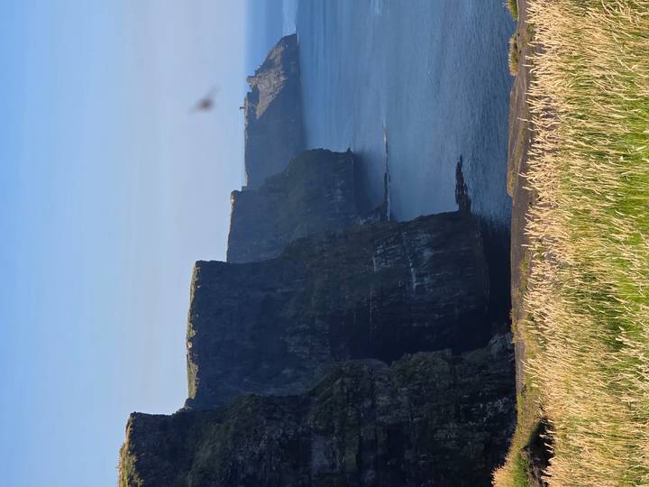 Dramatic sheer cliffs dropping into the Atlantic Ocean under clear blue sky