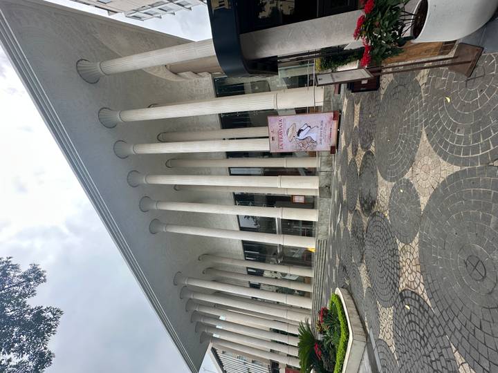 Modern neoclassical building with tall white columns and a poster advertising La Traviata at its entrance.