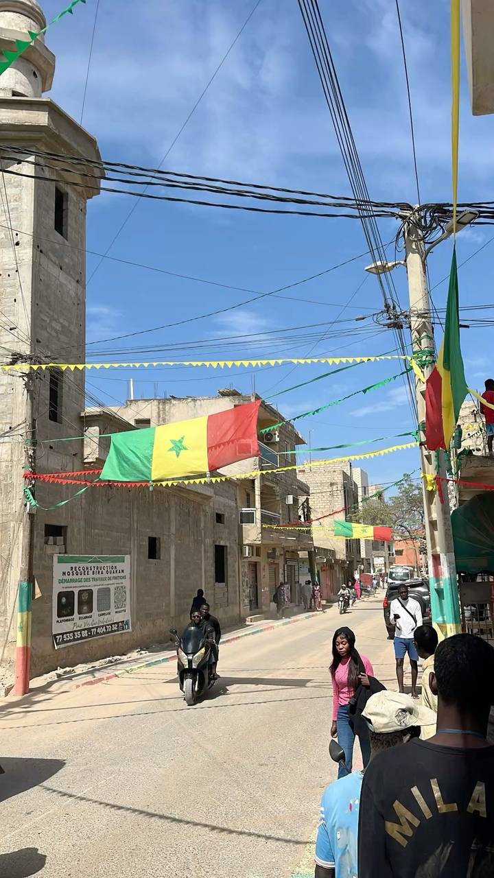 City street festooned with red-yellow-green Senegalese flags and colorful pennants
