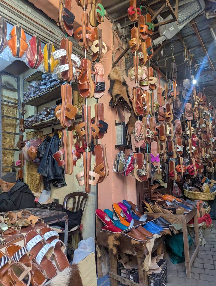 Wall of hanging handmade leather sandals in a busy Moroccan souk stall