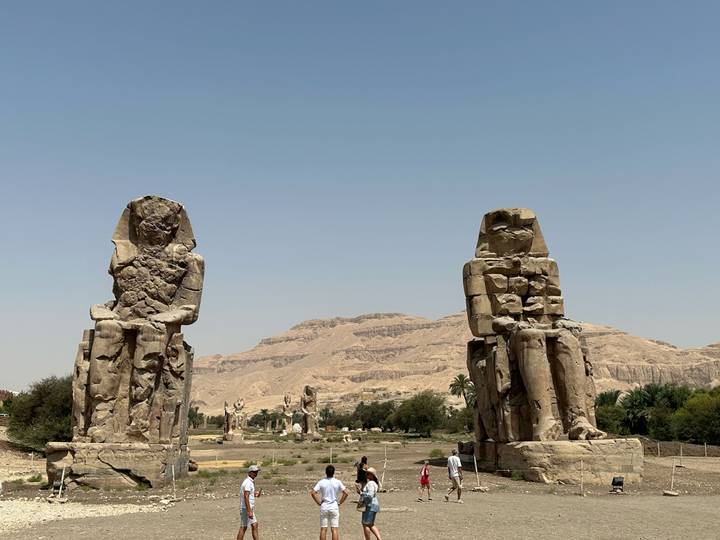 The Colossi of Memnon statues standing tall with arid mountains in the background.