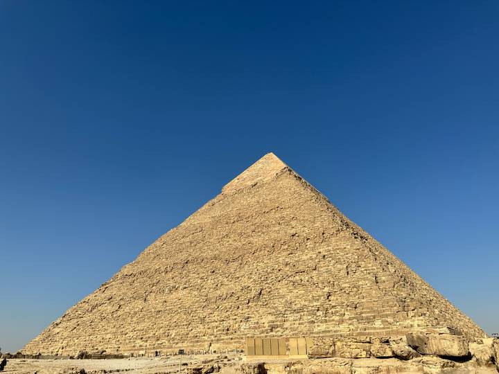Dramatic perspective looking up one face of the Great Pyramid of Giza against deep blue sky.