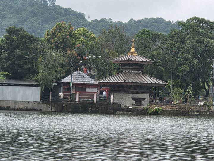 Small pagoda-style Barahi Temple on an island with forested backdrop and lake in foreground.