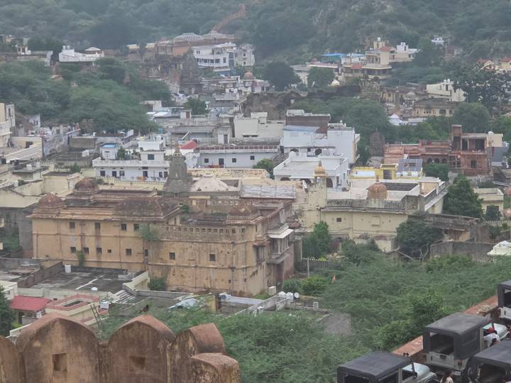 Elevated view across historic town with stone forts, temples and green trees.