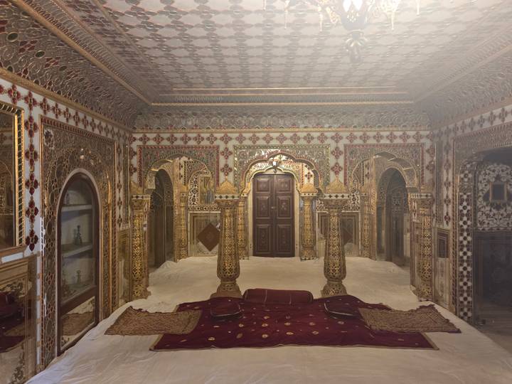 Lavishly mirrored and inlaid royal chamber with ornate arches and pillars in Amber Fort.