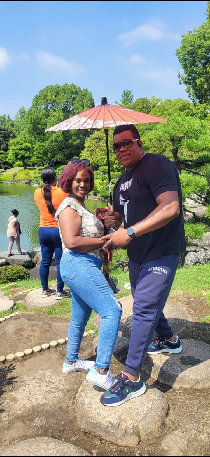 Couple posing by a tranquil pond in a Japanese garden holding an umbrella.
