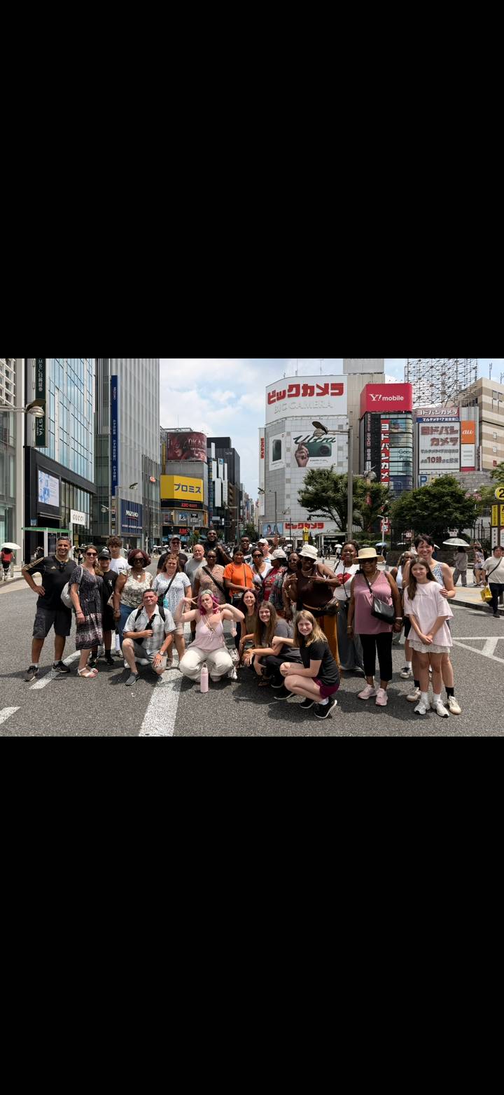 Large tour group gathered on a busy city street crossing in Tokyo for a photo.