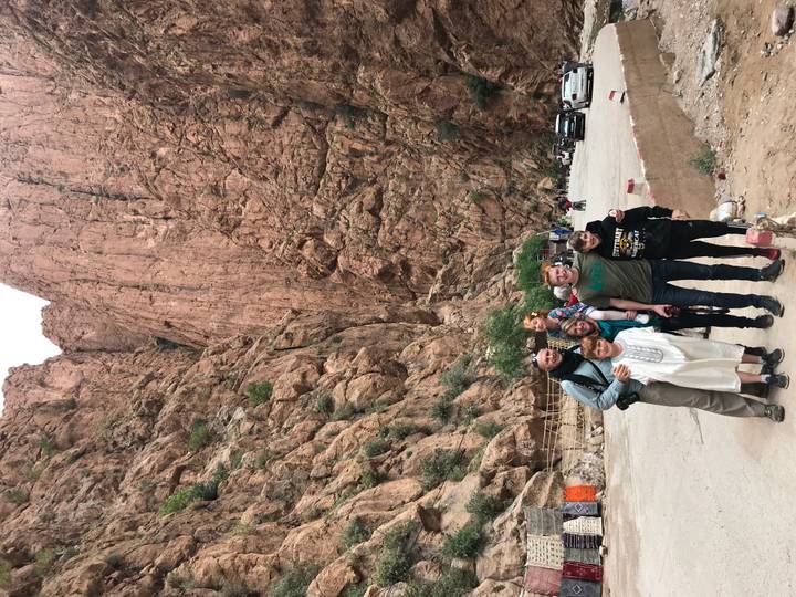 Family poses at the foot of towering rose-colored cliffs in a rocky gorge.