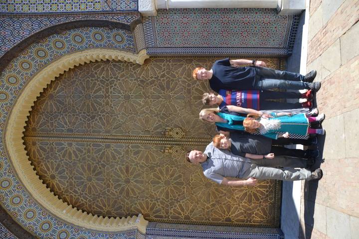 Family poses before an ornate golden door with intricate geometric patterns and mosaic arches.