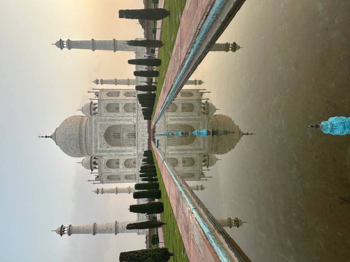 Symmetrical view of Taj Mahal reflected in central pool at dawn with soft pastel sky