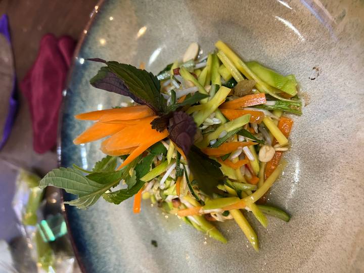 Plated Vietnamese mango and herb salad garnished with carved carrot flower.