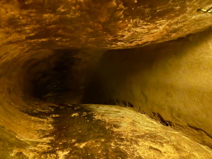 Dimly lit interior tunnel with earthen walls curving into darkness.