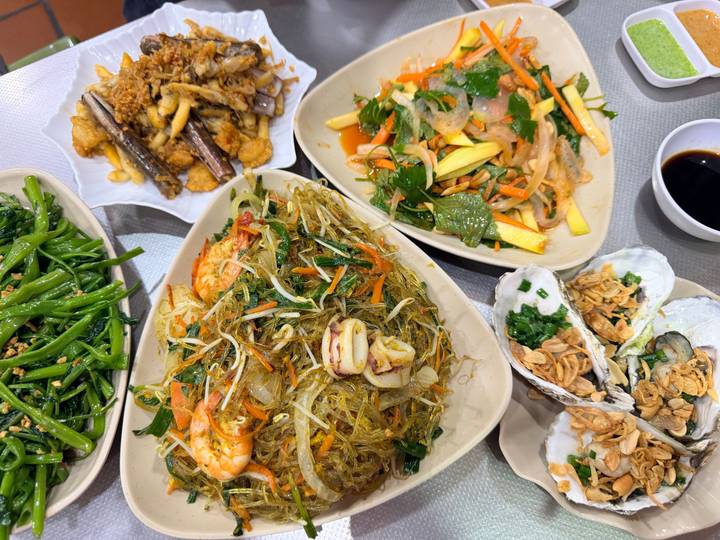 Variety of Vietnamese seafood and vegetable dishes served family-style on a restaurant table.