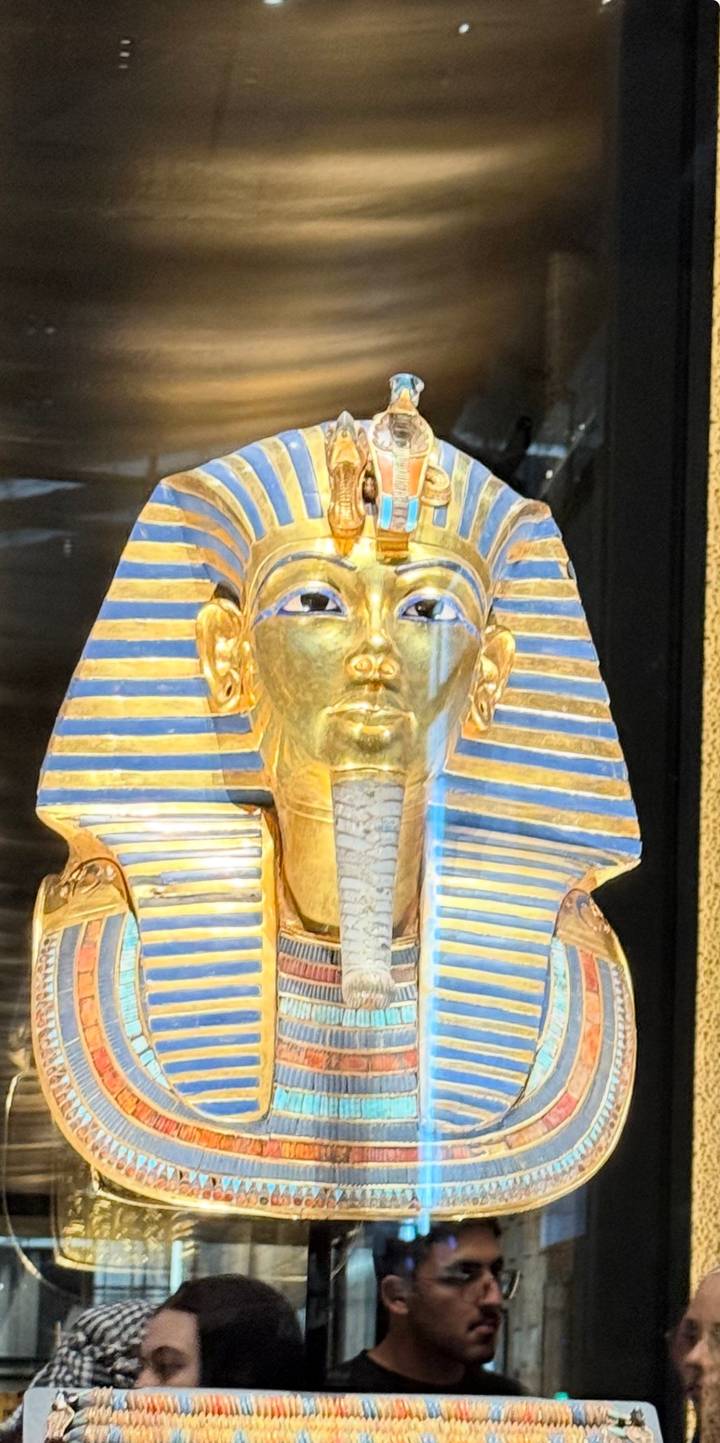 Close-up of the golden death mask of Tutankhamun displayed in a museum case.