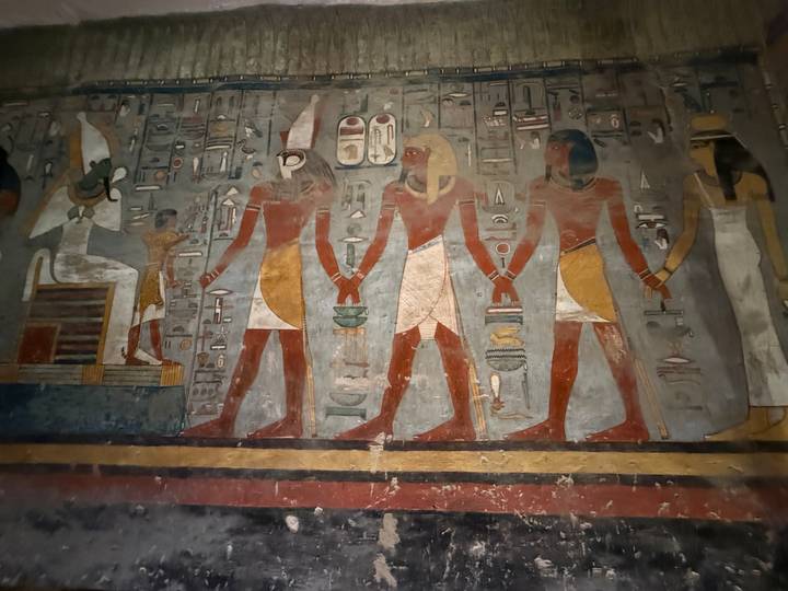 Ancient Egyptian wall painting depicting deities holding hands inside tomb.