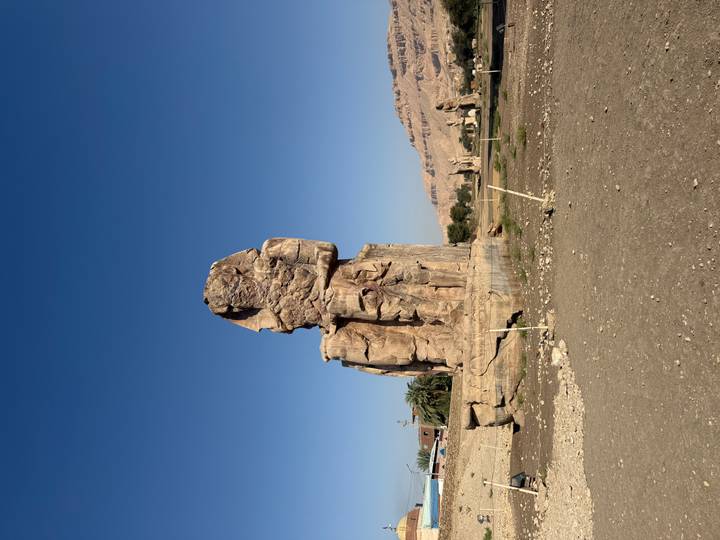 Colossus of Memnon statue standing solitary against clear blue sky in Luxor.